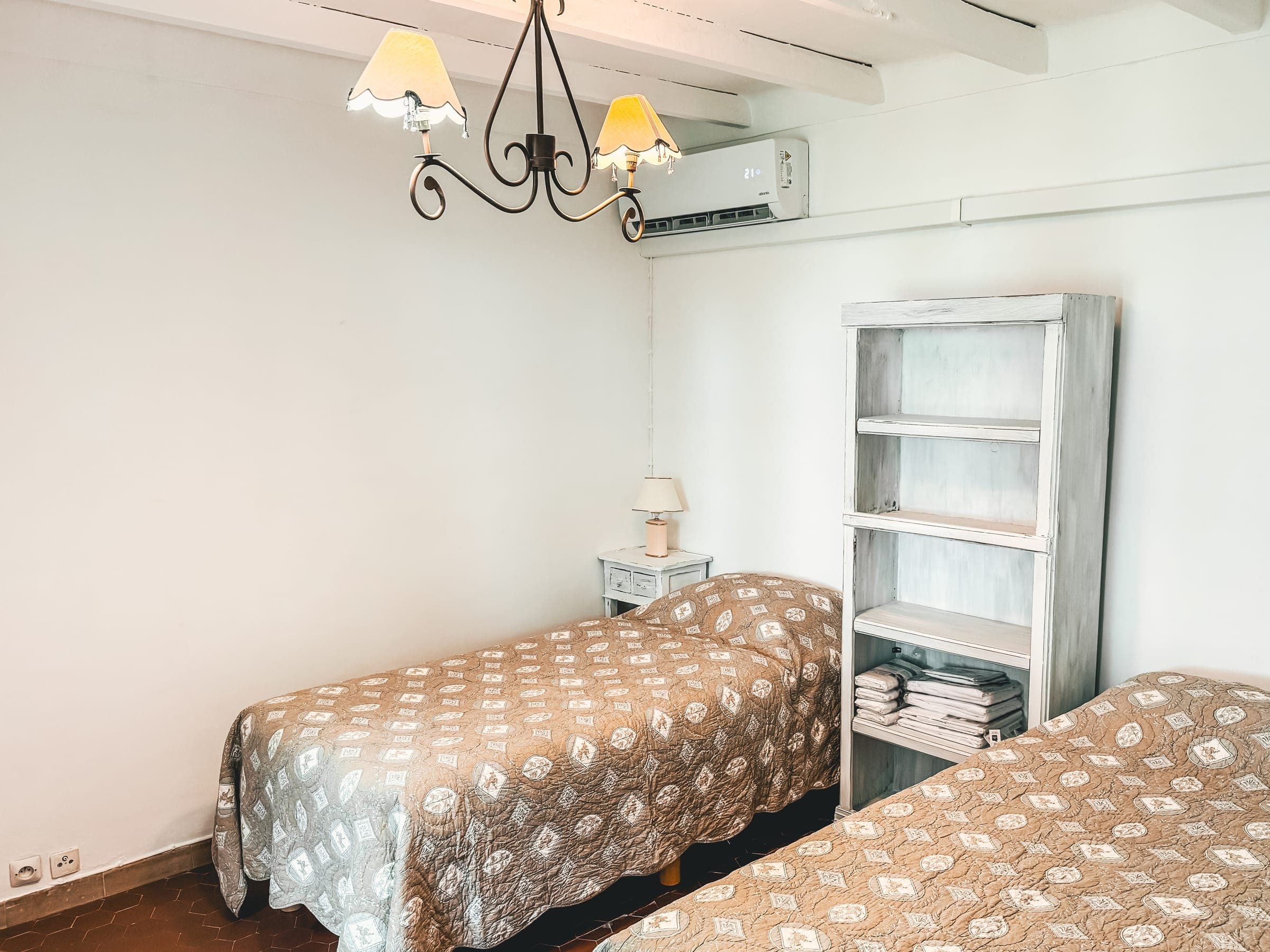 Light-filled bedroom with patterned bedspreads and white shelving