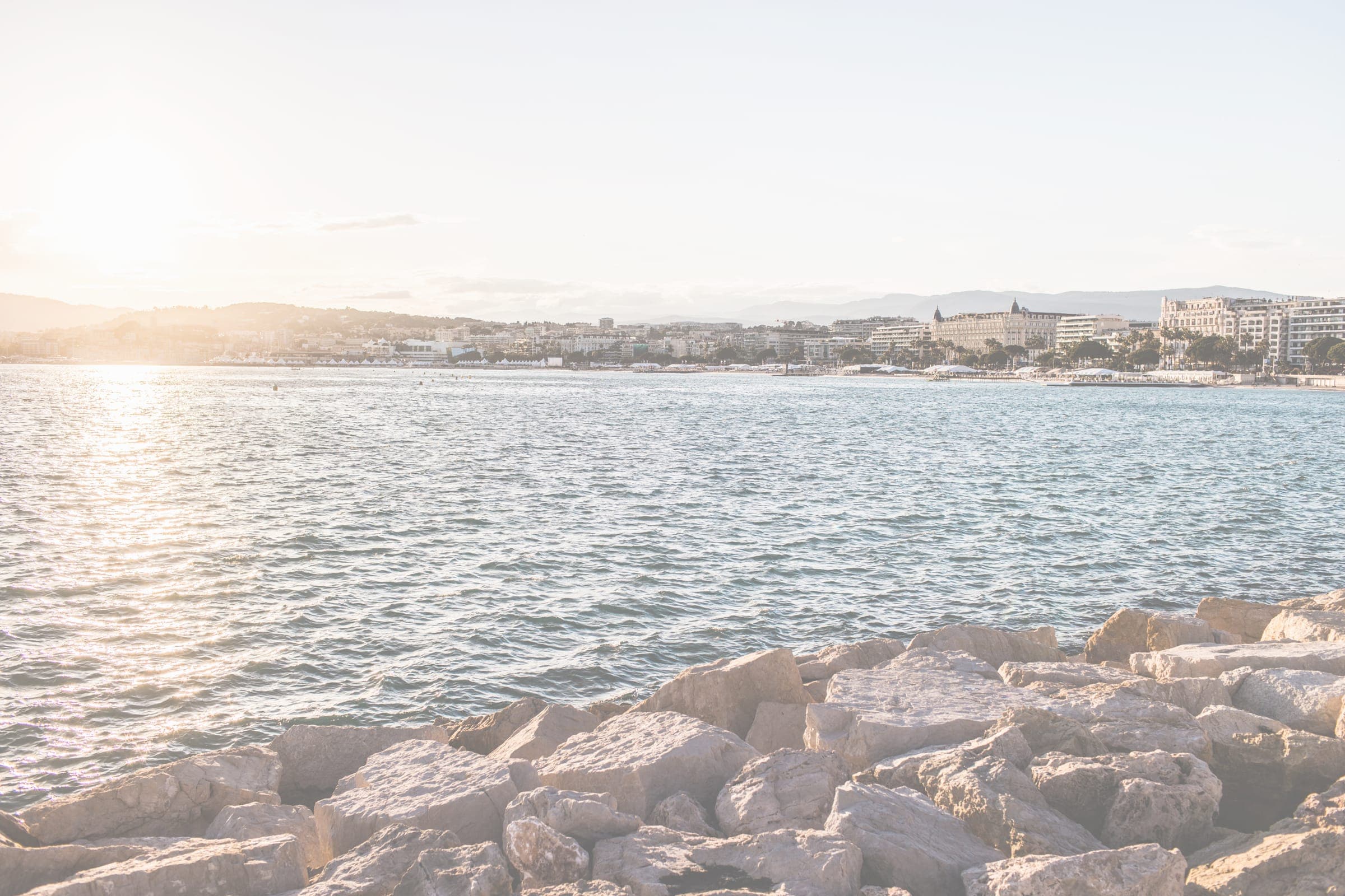 The bay of Cannes at sunset seen across the rocks