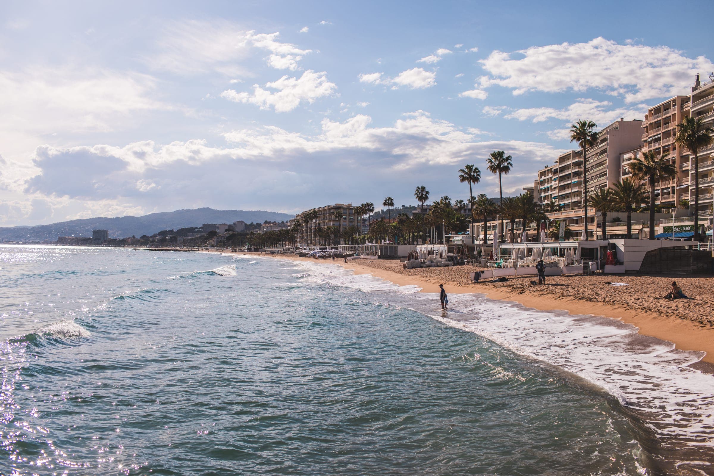 Waves on a Côte d’Azur beach lined with palm trees