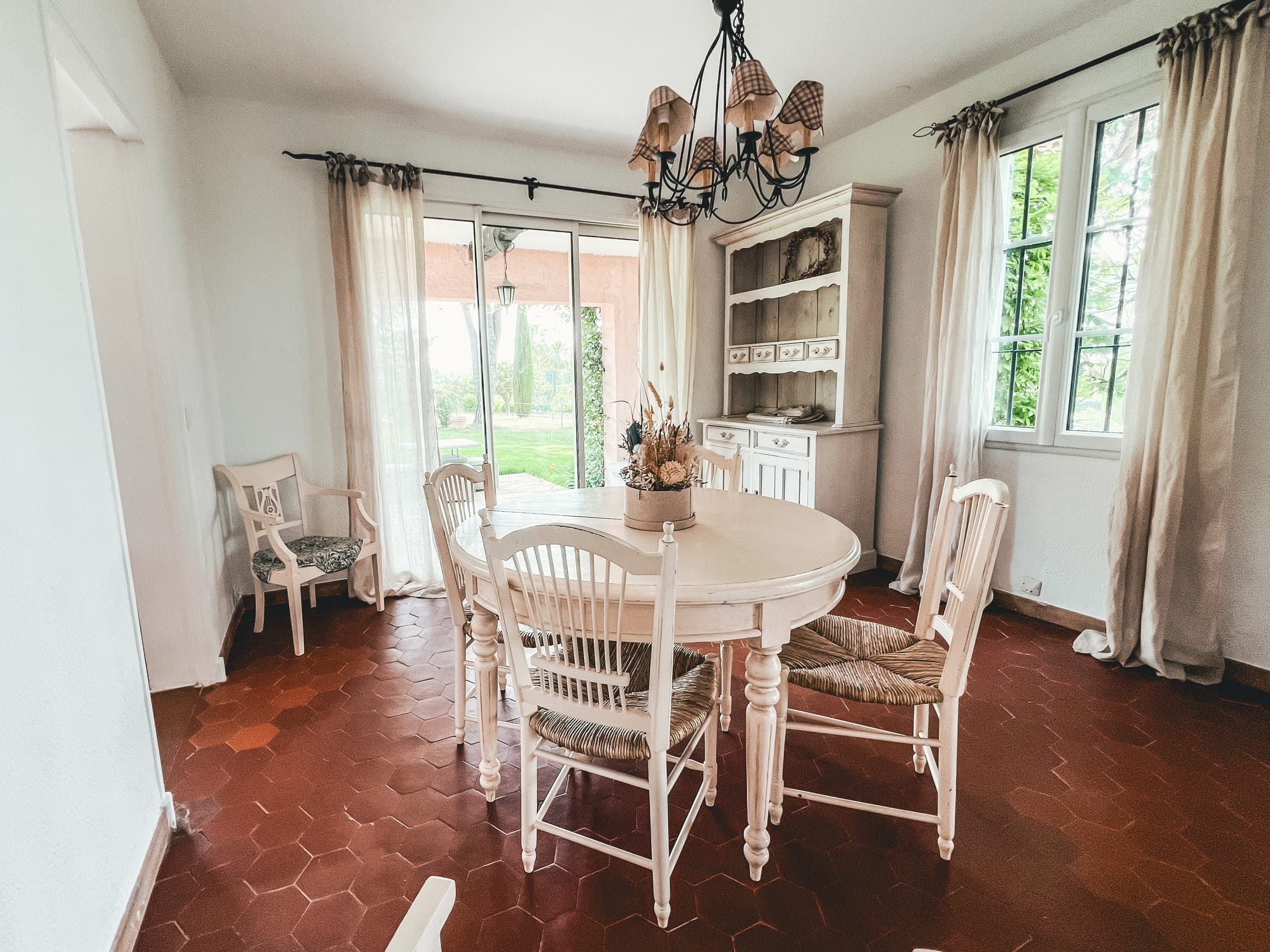 Bright dining room with a round white table, rush chairs and a chandelier
