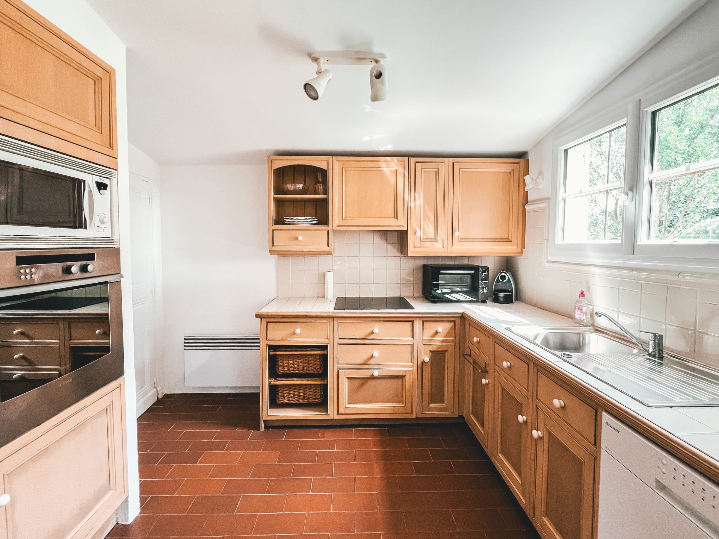 Fitted wooden kitchen with oven, hob and window onto the garden