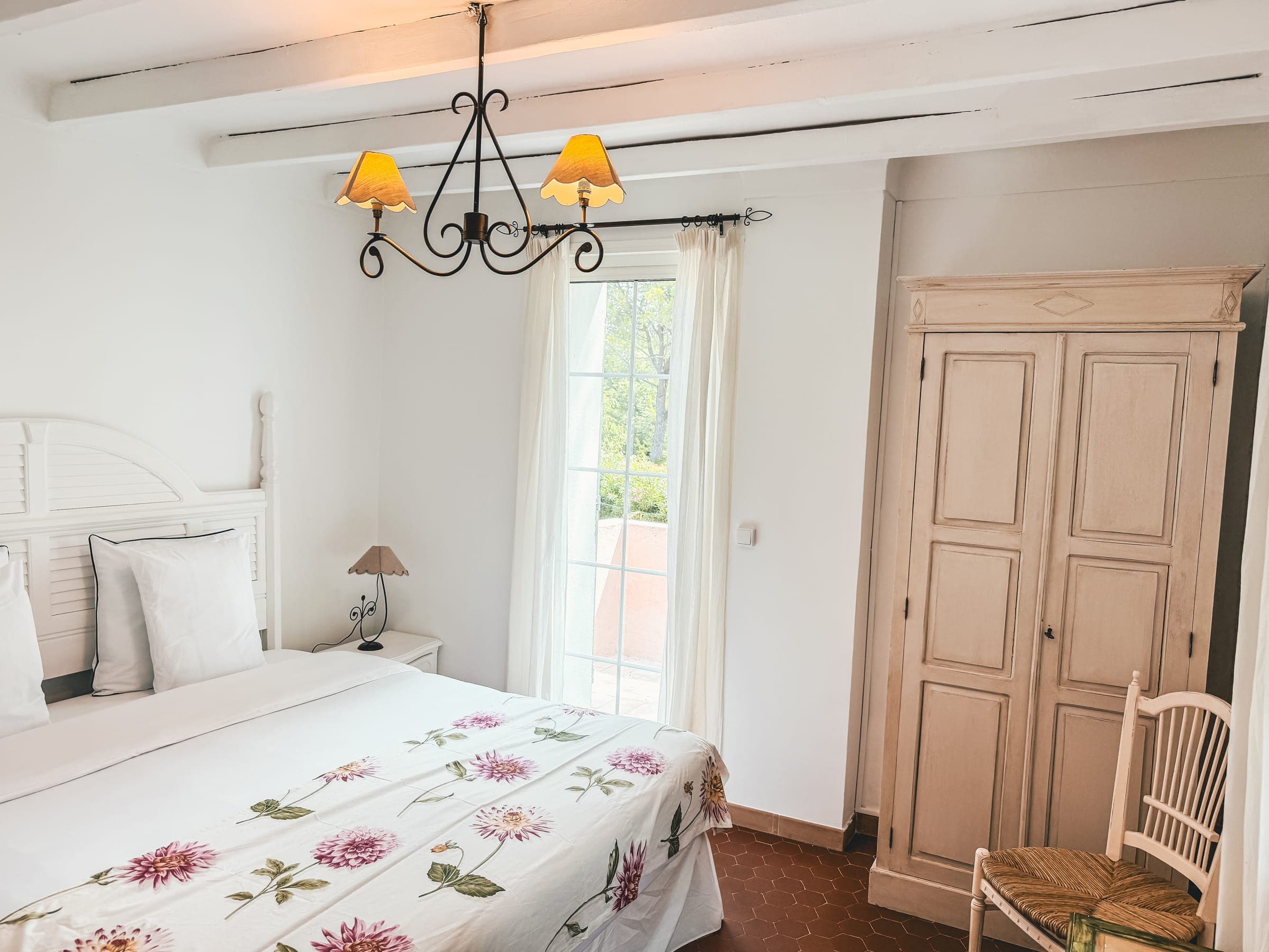 Master bedroom with floral bedspread, beamed ceiling and door to the terrace